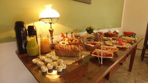 A buffet table with various food items, a coffee pot, and a decorative lamp. - Refúgio Tiradentes (Tiradentes)