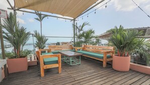 Eine Holzterrasse mit einer Couch, einem Tisch und Blumentöpfen.