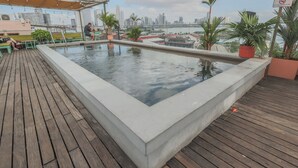 Ein Pool auf dem Dach mit Blick auf die Stadt, einer Holzterrasse und Kübelpflanzen.