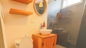 Ein Badezimmer mit Toilette, Holzschrank, Waschbecken und Dusche.