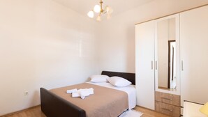 A bedroom with a bed, a wardrobe, a mirror, and a chandelier. - Beautiful apartment in Omis with lake view (Omis)
