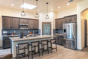 A modern kitchen with dark wood cabinets, stainless steel appliances, and a central island with bar stools.