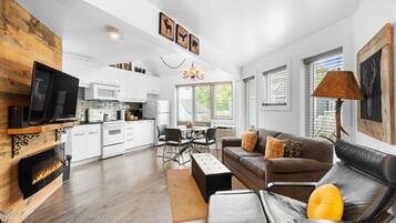 A modern living room with a fireplace, a dining area, and a kitchen.