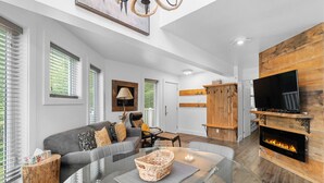A modern living room with a glass coffee table, grey sofa, and a fireplace.