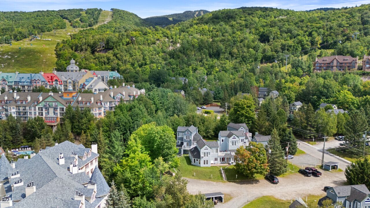 A residential area with houses, a large building with a driveway, and a hilly background.