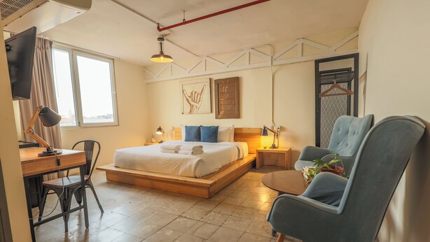 Una habitación de hotel moderna con cama, escritorio, silla y una mesita con una planta.
