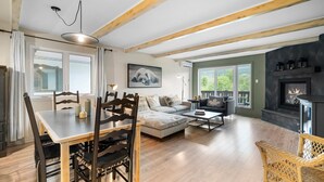 Un salón espacioso con chimenea, una zona de comedor con sillas de madera y un sofá.