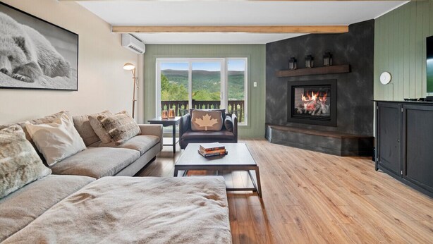 Una sala de estar acogedora con chimenea, un sofá, una mesita de centro y vistas al exterior.