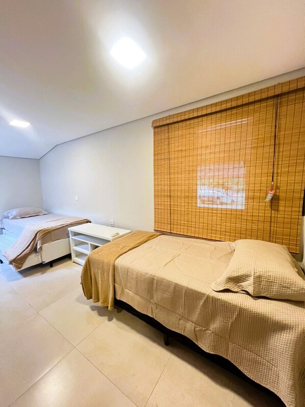 A bedroom with two beds, a white wardrobe, and a window with blinds.