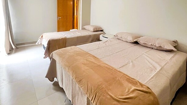 Une chambre d’hôtel avec deux lits, une porte et un interrupteur sur le mur.