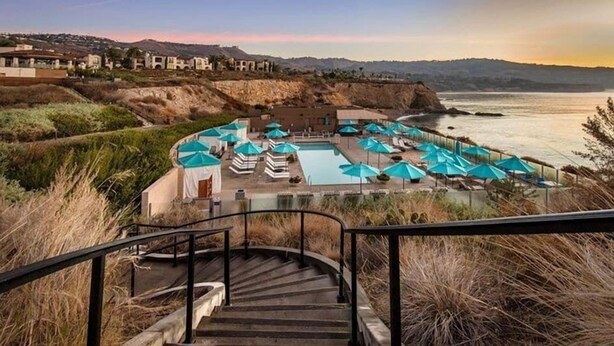 A resort with a pool area, outdoor seating, and a staircase leading to the pool.