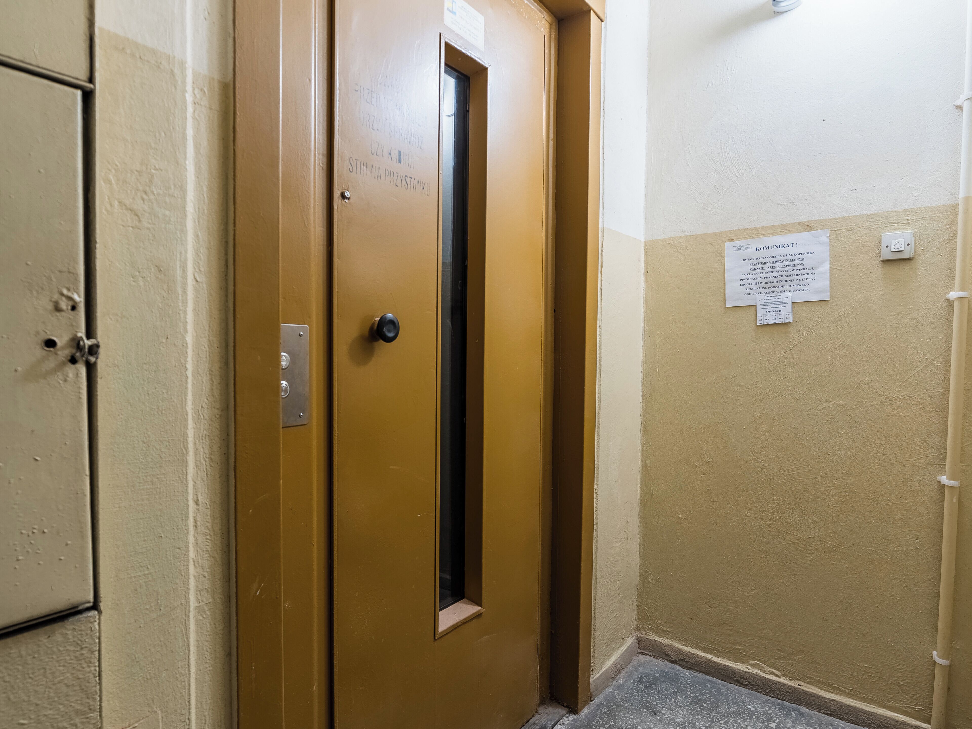 A door with a sign, a wall with a notice, and a light switch.