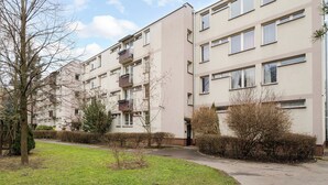 Un edificio residencial de varios pisos con balcones, un sendero empedrado y una zona ajardinada.