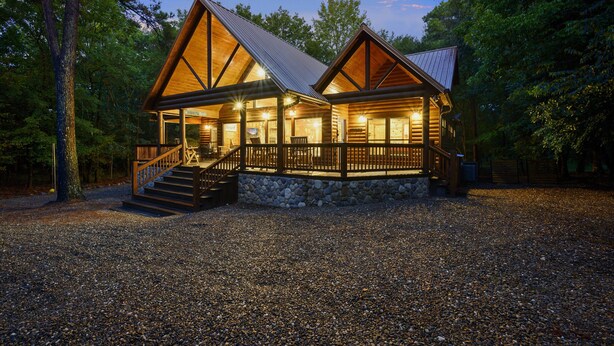A lodge with a stone foundation, wooden exterior, and a covered porch with steps leading to the entrance.