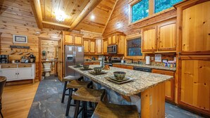 Una cocina amplia con armarios de madera, encimeras de granito y una isla central con taburetes de bar.