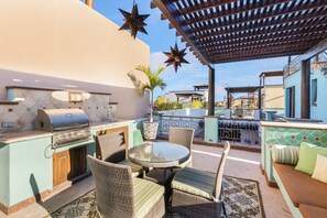 An outdoor patio with a grill, wicker furniture, and a view of the city.