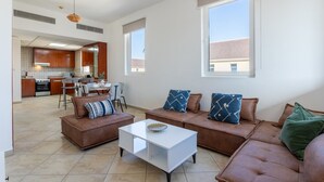A spacious living area with a sofa set, a coffee table, and a dining area with chairs and a table.