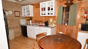 A compact kitchen with wooden cabinets, a dining table, and chairs.