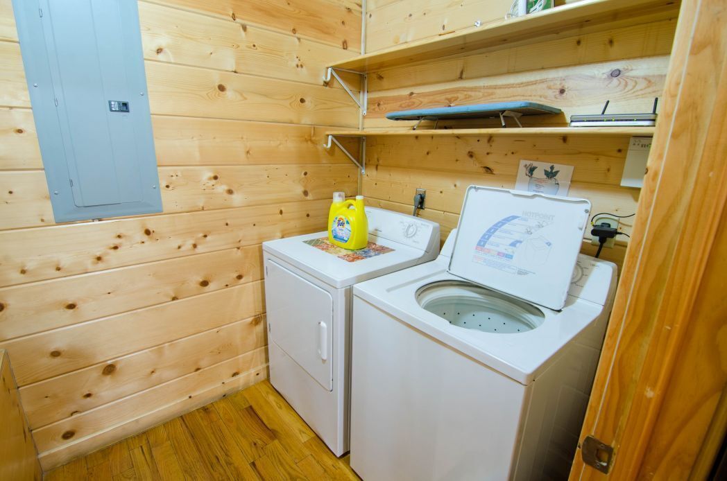 A compact laundry room with wooden walls and a washing machine.