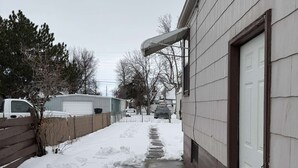 A snow-covered pathway leading to a house with a metal door and a small porch area. - Newly remodeled 2-bedroom house with WiFi, conveniently located in Great Falls (Great Falls)