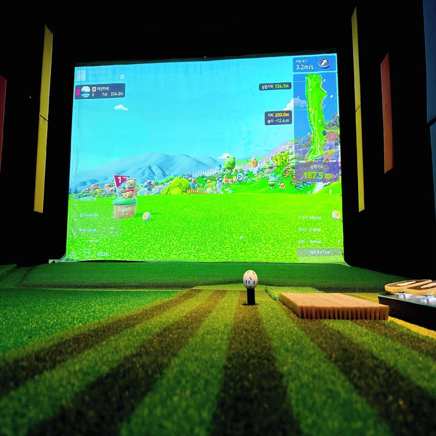 Simulación de un campo de golf en una pantalla grande, con una pelota y un palo de golf en primer plano.