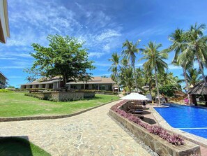 Ein Resort mit Swimmingpool, Palmen und einem Gebäude mit einem Ziegeldach.
