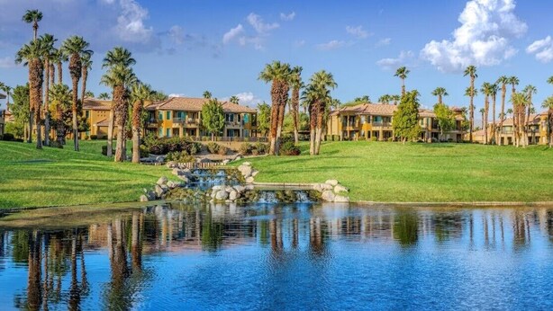 A resort with multiple buildings, a pond, and palm trees.