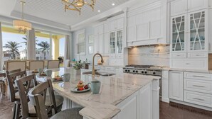 A spacious kitchen with white cabinetry, a large island, and a dining area with chairs and a table. - Ocean View, Gulf Access, Close to Beach, Private heated Pool - Island Waters  - Roelens (Fort Myers Beach)