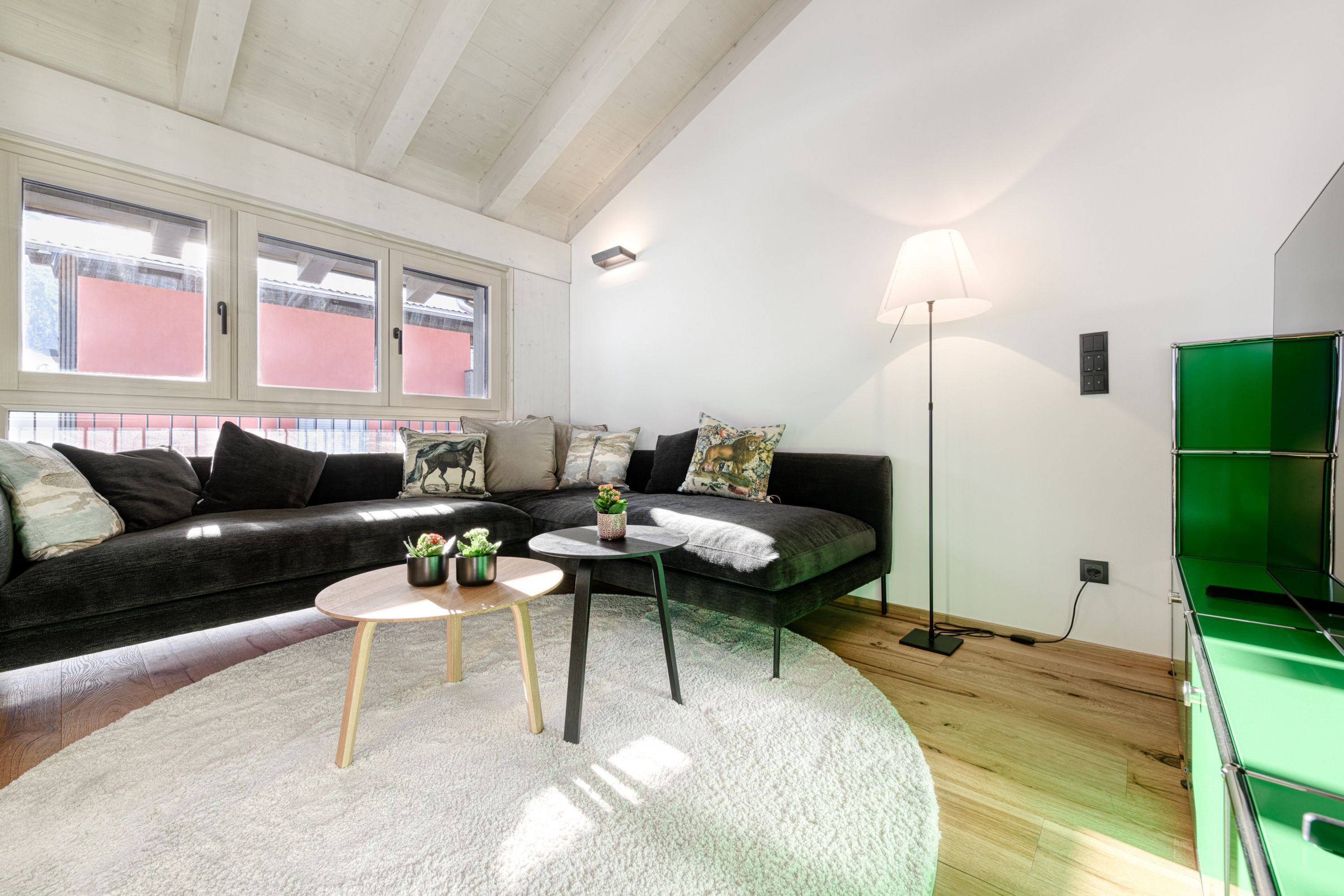 Un salon moderne avec un canapé de couleur foncée, une table basse ronde et un lampadaire.