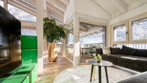 A modern living room with a green sofa, a round coffee table, and a large plant. - Luxus Penthouse Zentral (Brand)