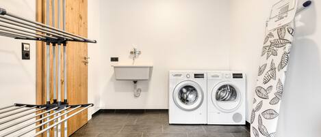 Een wasruimte met een droogrek, wasmachine en gootsteen.