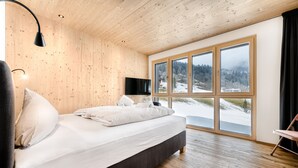 A bedroom with a bed, a TV, and a large window with a view of a snowy landscape. - Ferienwohnung Family Zentral (Brand)