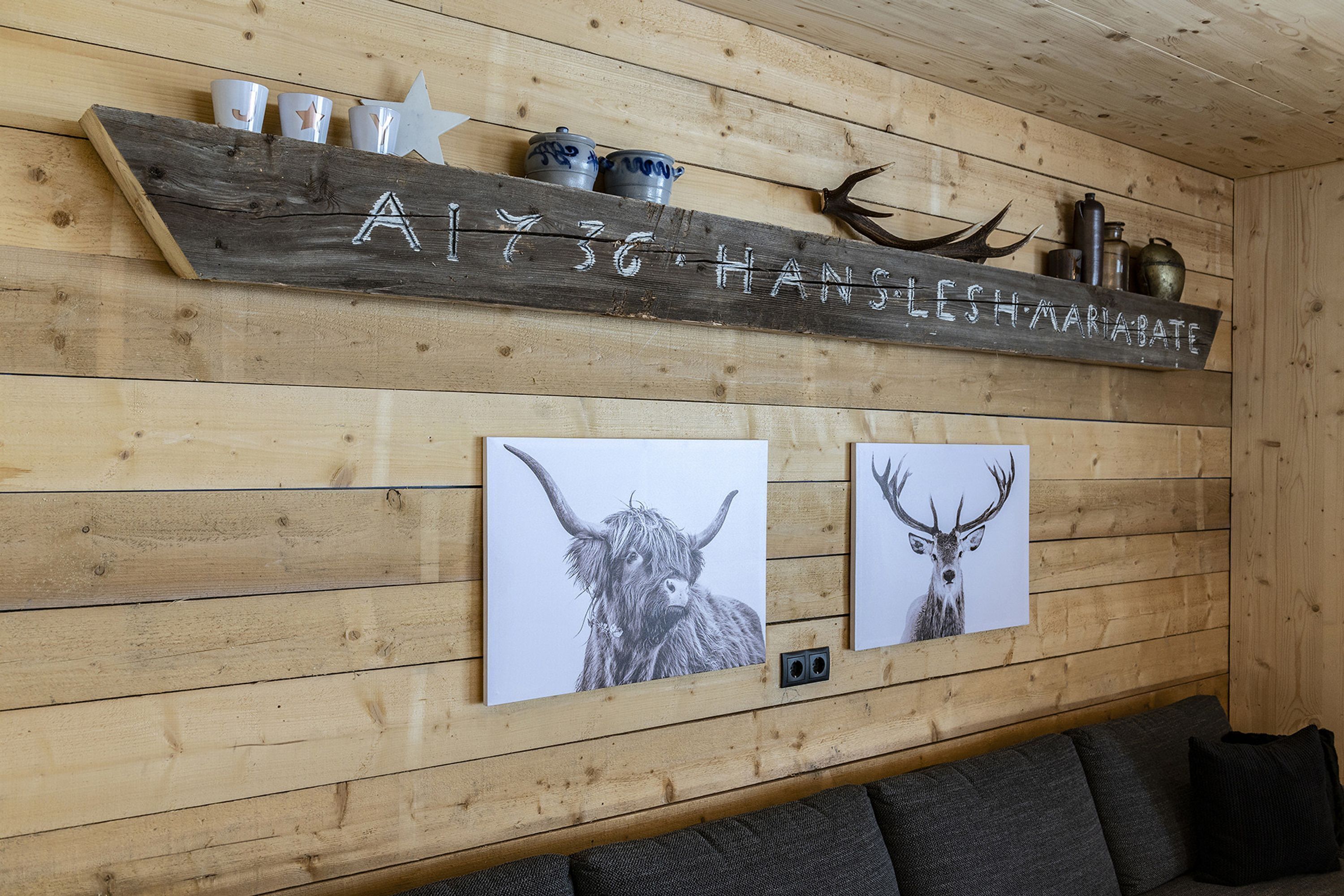 A wooden wall with a mounted shelf displaying a sign, two framed animal prints, and decorative items.