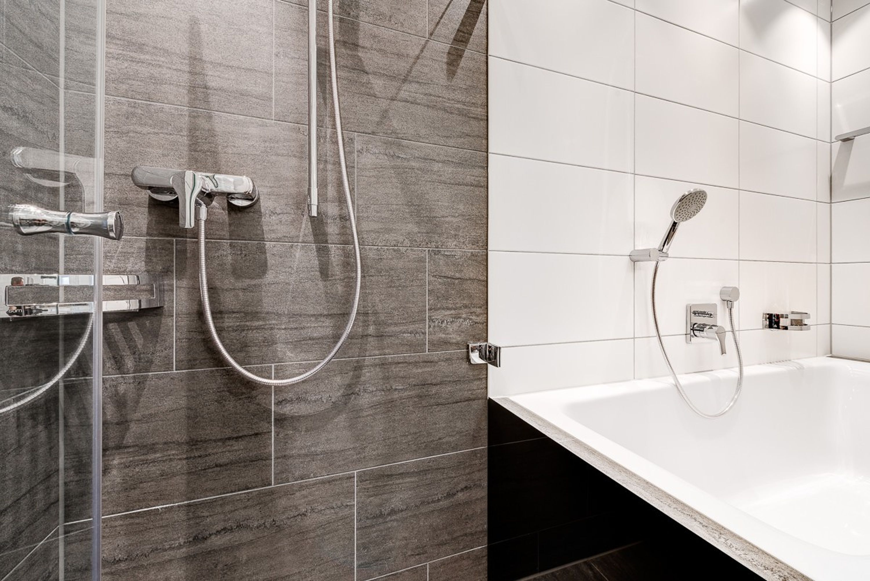 A modern bathroom with a shower, a bathtub, and a handheld showerhead.