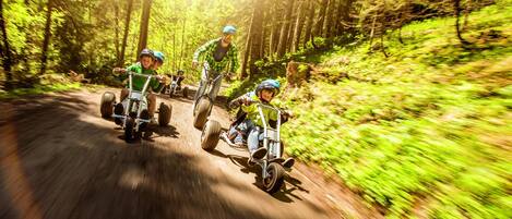 A group of people on a dirt bike trail surrounded by dense forest.