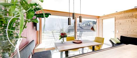 Ein moderner Essbereich mit einem Holztisch, gelben Stühlen und einer Blumenvase.