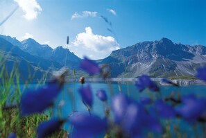 Un paysage montagneux avec un lac aux eaux limpides et des montagnes à l’horizon.