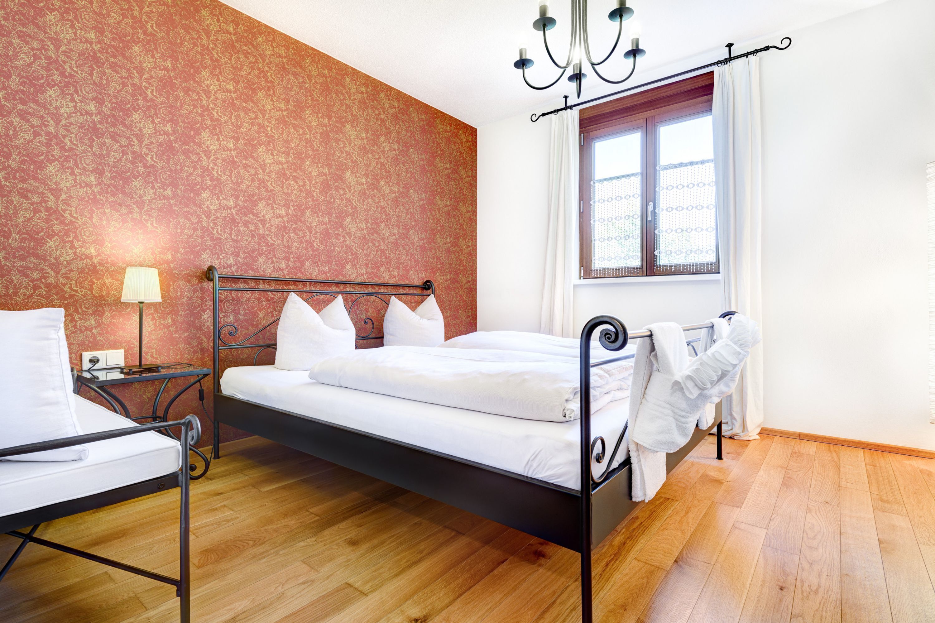 Una camera da letto con un letto, un comodino, una lampada e una finestra con tende.
