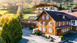 A multi-story hotel with a traditional European architectural style, featuring a prominent entrance, multiple balconies, and a well-maintained garden area. - Familiennest Zentral (Brand)