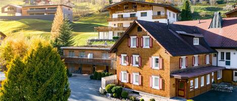 A multi-story hotel with a traditional European architectural style, featuring a prominent entrance, multiple balconies, and a well-maintained garden area.