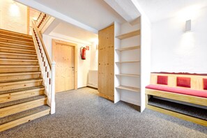 A staircase leading to a landing with a wooden bench and a radiator. - Familiennest Zentral (Brand)