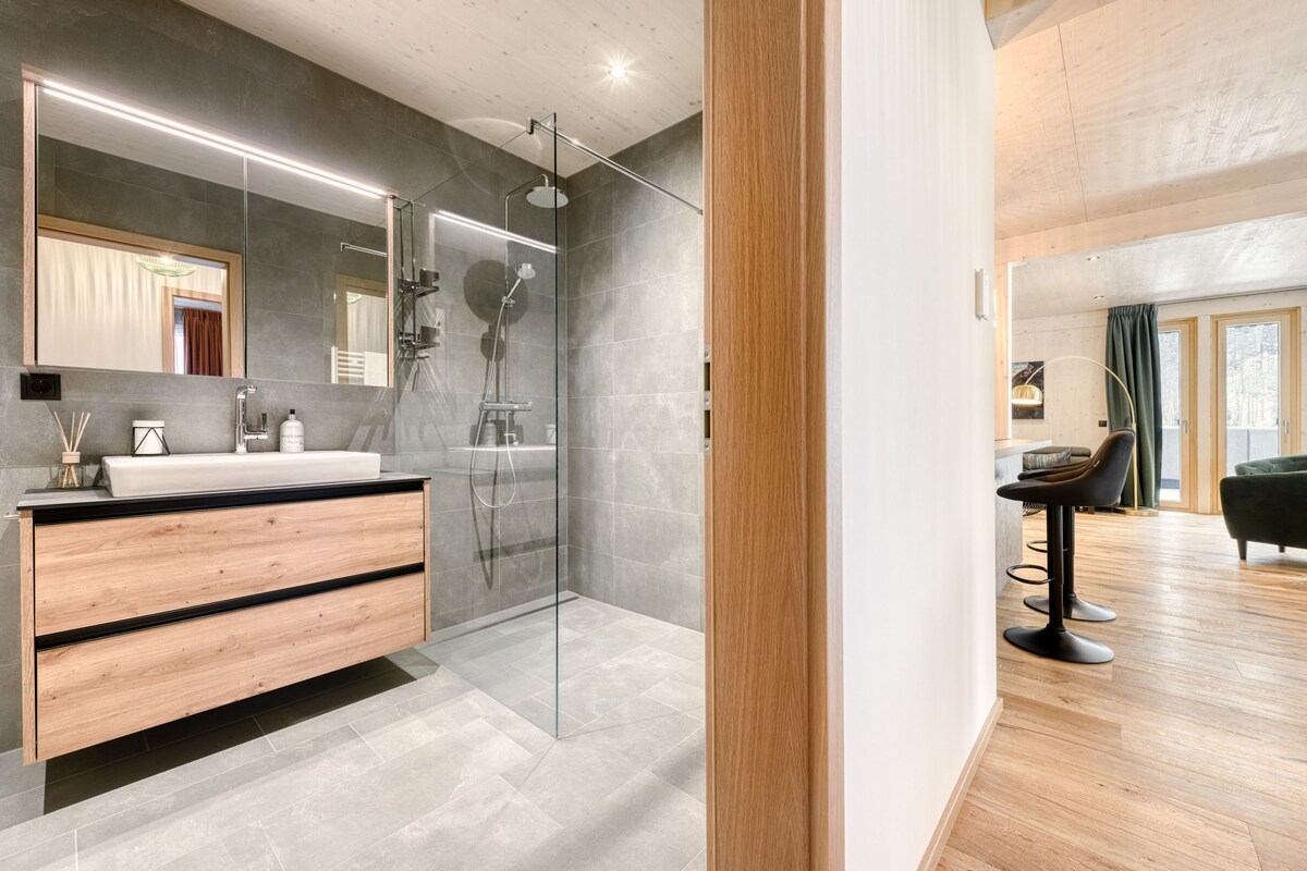 Une salle de bain moderne avec une douche à parois de verre, un meuble-lavabo en bois et un grand miroir.
