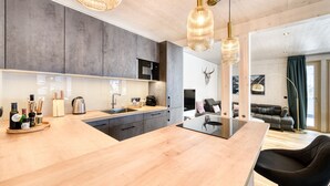 A modern kitchen with a central island, grey cabinets, and a dining area with black chairs. - Familienferienwohnung Zentral (Brand)