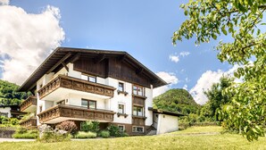 Un immeuble à plusieurs étages doté de balcons, entouré de verdure et surplombant un ciel dégagé.