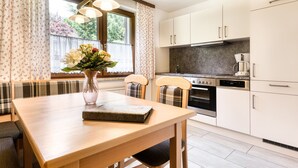 Une cuisine moderne avec des armoires blanches, un four encastré et un coin repas comprenant une table et des chaises en bois.
