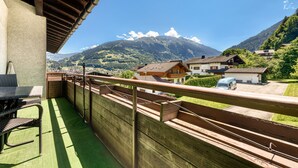 Un balcon avec vue sur une montagne, une table et des chaises.