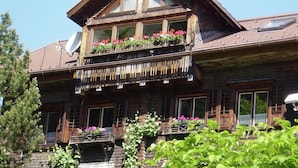 A wooden chalet with a balcony adorned with flowers, a sloped roof, and a wooden facade. - Chalet Fischer in B Rserberg (Buerserberg)
