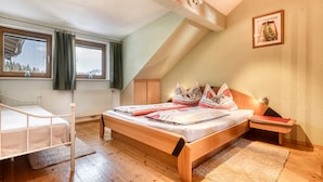 A bedroom with a wooden bed, a window with curtains, a radiator, and a framed picture on the wall. - Chalet Fischer in B Rserberg (Buerserberg)