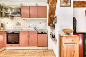 Uma cozinha com armários rosa, forno de aço inoxidável e lava-louças.