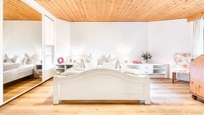 A bedroom with a white bed, wooden ceiling, and a large mirror. - Chalet Zentral Bach in Brand (Brand)
